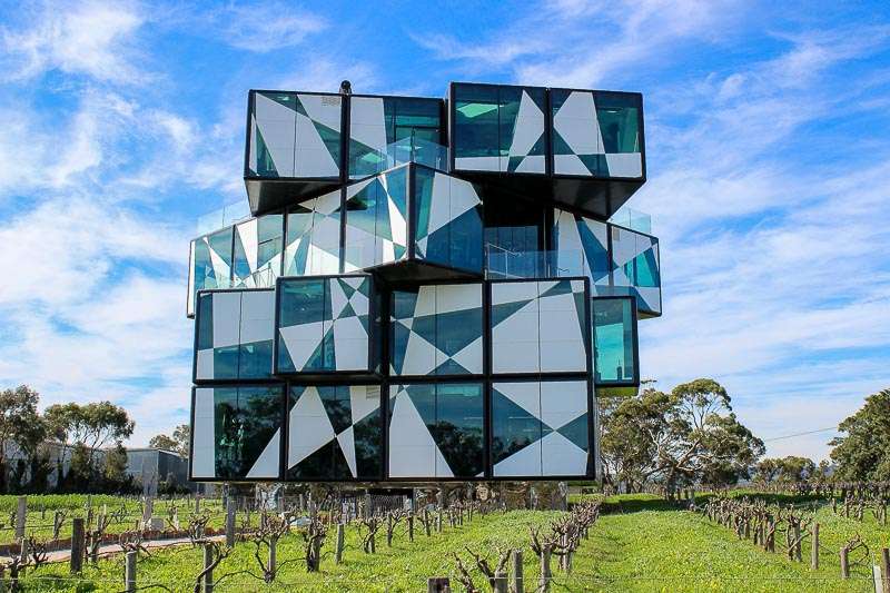 The D'Arenberg Cube cellar door. A distinctive building sits amongst bare grape vines. The building is black and white, shaped like a four-layer Rubiks cube with the top two layers twisted slightly.