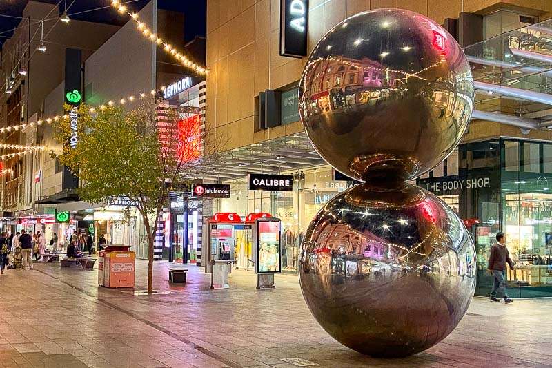 Two large metal balls in the middle of a city street.