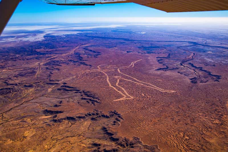 Photo from a plane looking down at a huge carving of an Aboriginal man in the red dirt of the South Australia Outback